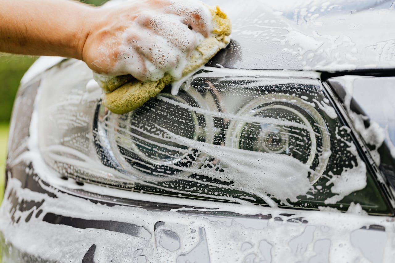 The Art of Drawing Readers In: Your attractive post title goes here Hand scrubbing a car headlight with sponge and soap suds, detailing process.